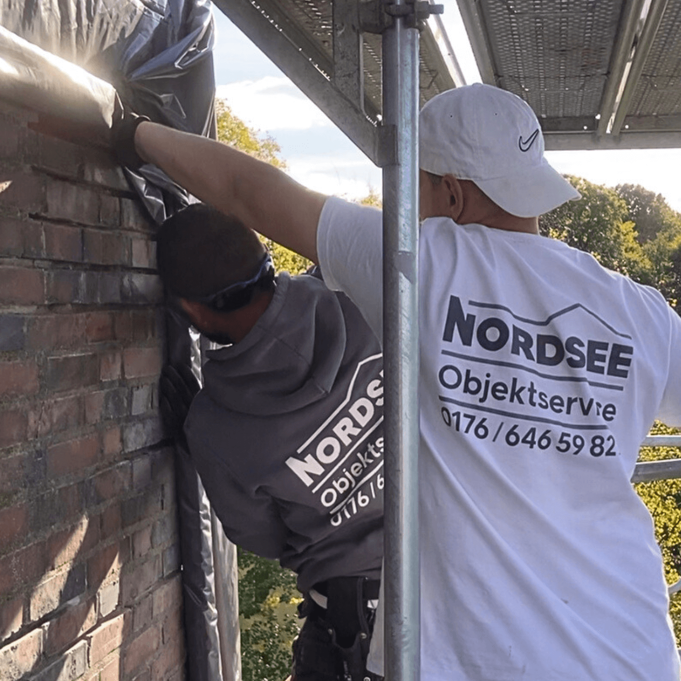 Zwei Mitarbeiter arbeiten gemeinsam auf einem Gerüst in Varel – Teamarbeit im Handwerk